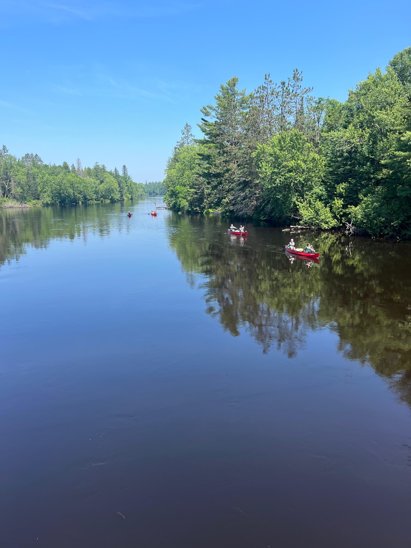 Chadash campers paddling red canoes down a glassy Wisconsin river