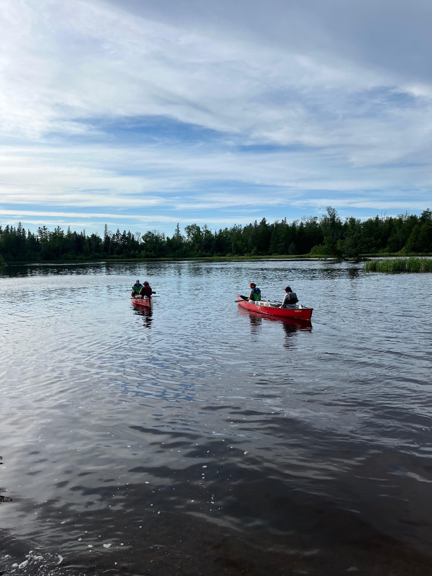Two canoes drifting on a still lake at dusk